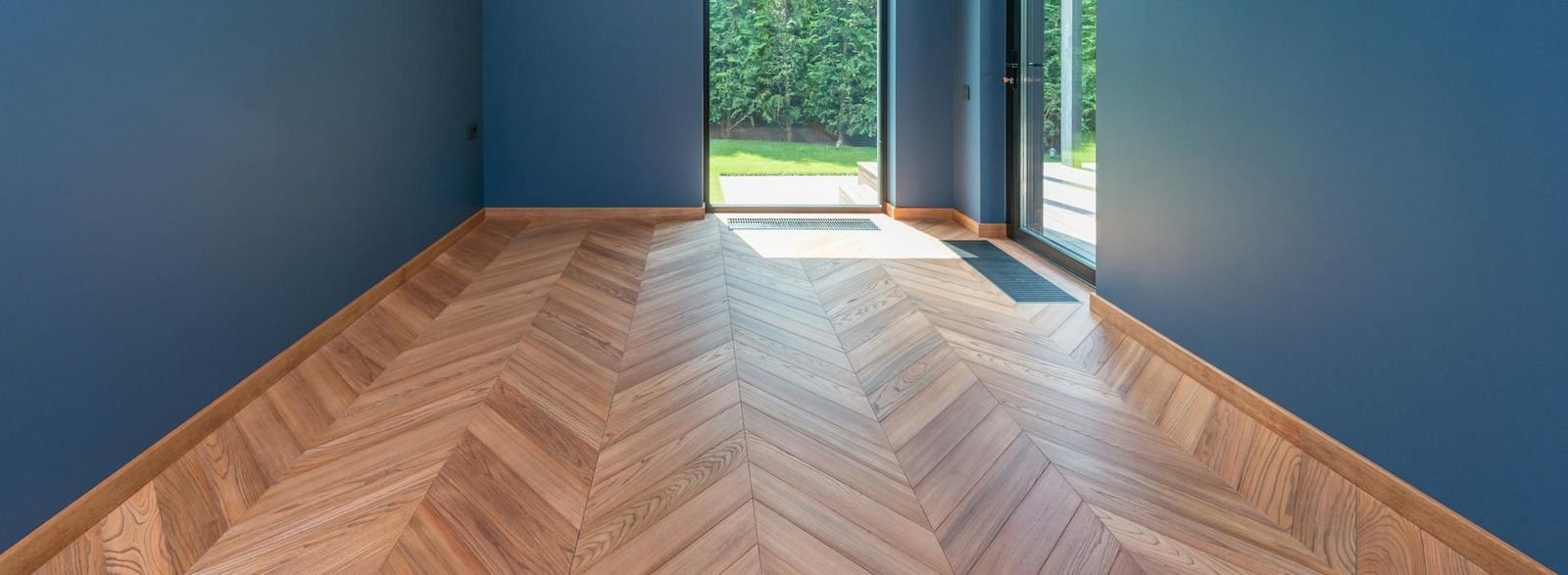Tarima de roble natural en patrón chevron instalada en salón moderno con luz natural — instalación profesional de parquet en España